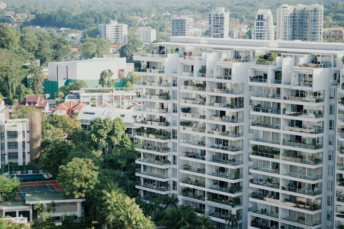 A white apartment block with balconies among trees